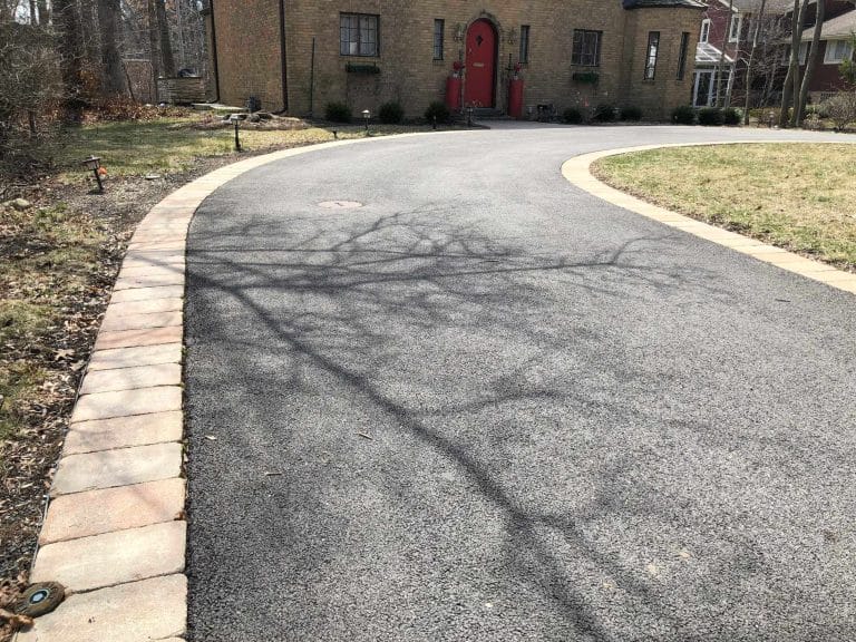 Curved Asphalt Driveway with Brick Edging in Residential Area
