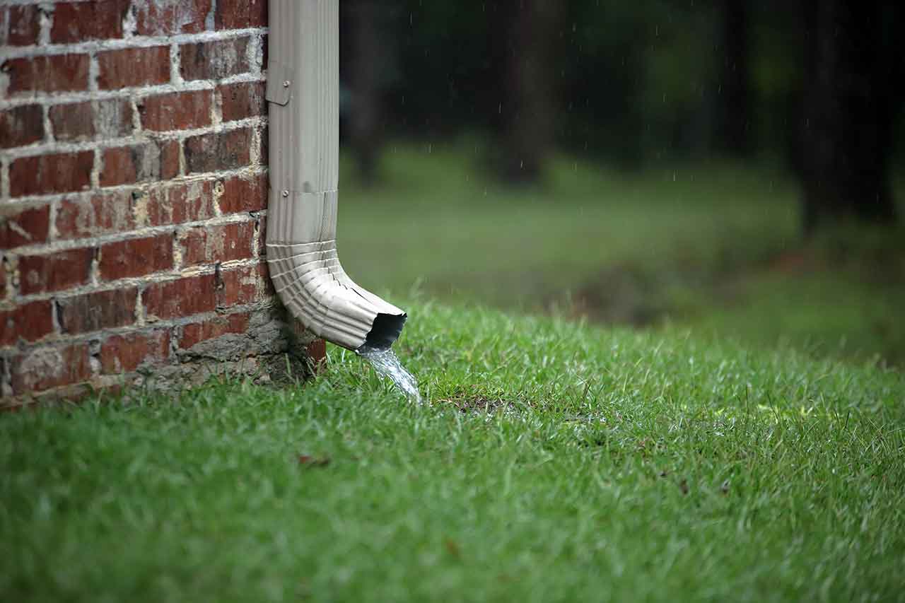 Stock image of a downspout clearing out water.